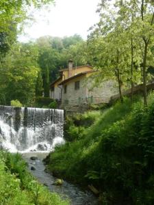 a waterfall in front of a house next to a creek at Mulino del XVII secolo in Borgo a Buggiano