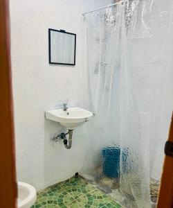 a bathroom with a sink and a shower curtain at Cockatoo Room Rentals Siquijor in Siquijor
