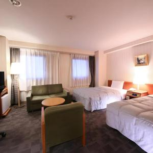 a hotel room with two beds and a couch at Centia Hotel Naito in Kofu
