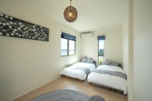 a bedroom with two beds and a chandelier at 湘南sajima stay in Yokosuka
