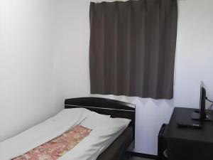 a bedroom with a bed and a desk and a window at Business Hotel Oise in Nagoya