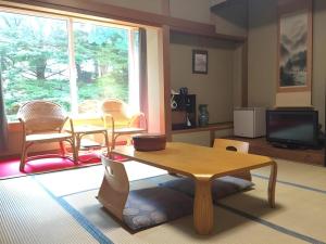 Una sala de estar con una mesa y sillas y un televisor. en Hotel Gomi, en Shinryū