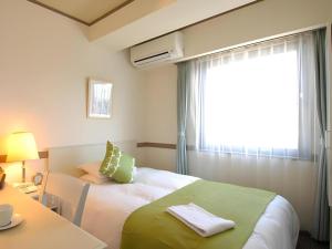 Un dormitorio con una cama grande con ventana. en Matsumoto Wellton Hotel, en Koyanagichō