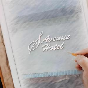 S Avenue Hotel في جوهور باهرو: شخص يحمل قلم رصاص أمام لافتة