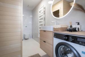 a bathroom with a washing machine and a mirror at TRITA SK - Lebenski A27 - Infrasauna - Brand new - Parking in Vysoké Tatry
