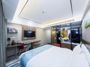 a bedroom with a bed and a desk and a tv at Borrman Hotel Zhenjiang Dashikou Suning Plaza in Zhenjiang