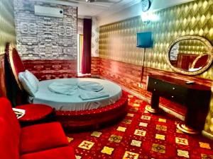a room with a bed and a chair and a mirror at Ultimate Ballagio G-8 in Islamabad