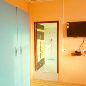 a room with an orange wall with a mirror and a tv at Perfect View Homestay in Cherrapunji