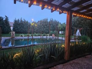 ein Garten mit beleuchtetem Pool und Pergola in der Unterkunft Lubię Nic przytulny dom z basenem in Mełgiew