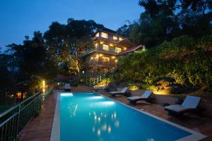 a house with a swimming pool in front of a house at Bamboo Dale Resort & Spa Munnar by Stride in Munnar