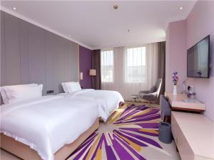 ein Hotelzimmer mit einem großen Bett und einem Fernseher in der Unterkunft Lavande Hotel Guangzhou Zengchen Xintang Light Railway Station in Zhongtang