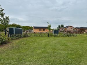 a yard with a fence and houses in the background at Empty camping spot for your tent, caravan and camper in Swalmen +4 photos
