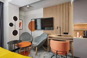 a hotel room with a desk and chairs and a bed at voco Katowice by IHG in Katowice