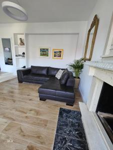 a living room with a black leather couch and a fireplace at Villa Mila in Korčula Town in Korčula