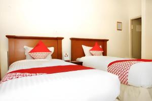 two beds with red pillows in a room at OYO 236 Penginapan Rumah Hijau in Sukarami +53 photos