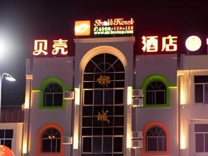 ein Gebäude mit Neonschildern in der Nacht in der Unterkunft Shell Qionghai Jinhai Road Hotel in Qionghai