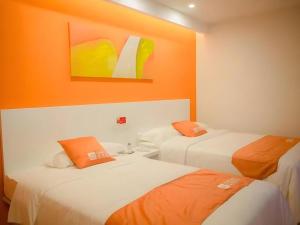 two beds in a room with an orange wall at Shell Qionghai Jinhai Road Hotel in Qionghai
