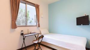 a bedroom with a bed and a desk and a window at Rich Reson ISHIGAKI in Fukai