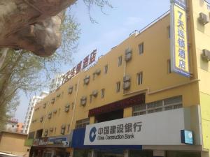 a yellow building with a sign in front of it at 7 Days Inn Yantai Dahaiyang Raod Railway Station in Yantai