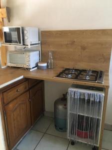 a kitchen counter with a stove and a microwave at Studio meublé Fréjus équipé d'une climatisation in Fréjus