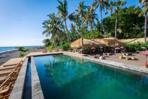 une piscine à côté d'une plage avec des palmiers dans l'établissement Beachfront Glamping - Escape in Nature, à Tianyar