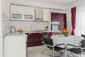 a kitchen with white cabinets and a table with chairs at Apartment Anna in Kaštela