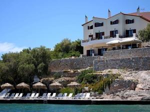 a building with chairs and umbrellas next to the water at Kekrifalia Hotel in Skala