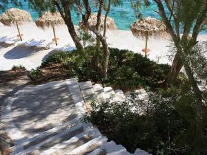 a beach with some straw umbrellas and the water at Kekrifalia Hotel in Skala