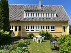 a yellow house with a table and chairs in the yard at Aliise Garden Guesthause in Pärnu