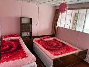a bedroom with two beds with red sheets and a window at Aliise Garden Guesthause in Pärnu
