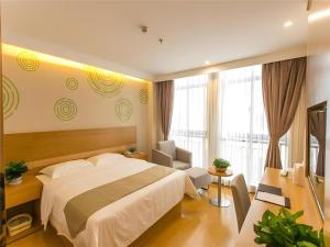 ein Hotelzimmer mit einem großen Bett und einem Stuhl in der Unterkunft GreenTree Inn Suzhou North Zhongshan Road Weiye Yingchun Plaza Business Hotel in Suzhou + 142 Fotos