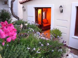 um jardim com flores cor-de-rosa em frente a uma casa em Kekrifalia Hotel em Skala