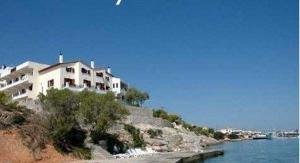 a white house on a hill next to the water at Kekrifalia Hotel in Skala