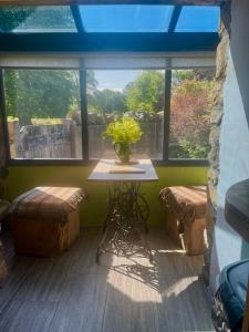 a table with a vase of flowers in a room with windows at The Brew House in Maulds Meaburn