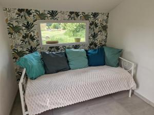 un banco con almohadas en una habitación con ventana en MAISON à la CAMPAGNE, en Hommes