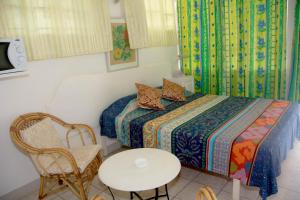 a bedroom with a bed and a chair and a table at Welcome Holidays in Grand Baie