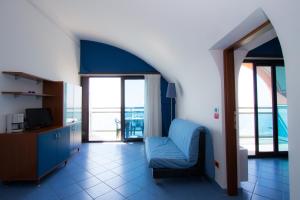 una sala de estar con una silla azul y ventanas en Residence Florida, en Caorle