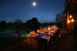 una mesa larga con velas en una cubierta por la noche en Nkasa Lupala Tented Lodge, en Sangwali