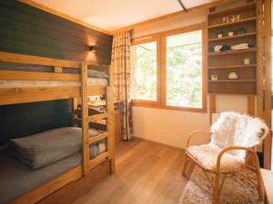 a bedroom with bunk beds and a chair and a window at Studio-cabine au pied des pistes avec terrasse de plain-pied in Valmorel