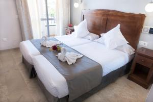 a bed with a white comforter and pillows at Hotel Toboso Chaparil in Nerja