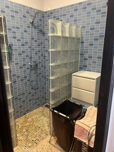 a blue tiled bathroom with a shower and a trash can at Villa Angelita in Creixell +15 photos