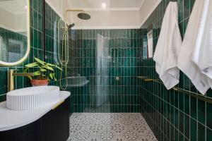 a green tiled bathroom with a sink and a toilet at The Carrington Cottage 
