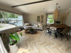 a living room with a table and a couch at Wild Flower Wellness met privé Sauna en Hottub in prachtige tuin met overkapping in Hoenderloo