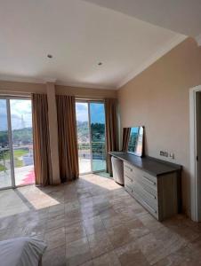 a bedroom with a bed and a dresser and windows at HallMark In East Legon by Mondasan Properties in Accra