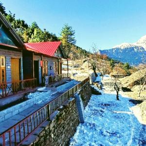a house next to a river with snow on the ground at Alta Vista Resort in Joshīmath