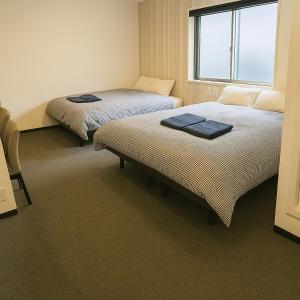 a room with two beds and a window at Port House Honmachi in Tokyo