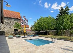 una piscina in un cortile con un edificio in mattoni di Le Clos de Joux - Charmante Maison en Bourgogne a Joux-la-Ville