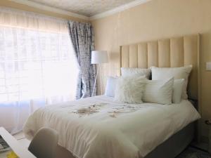 a bedroom with a large white bed with a window at Blanc and Bold in Kempton Park