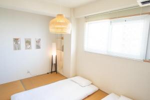 Una habitación blanca con una cama y una ventana. en ハレルヤ石垣, en Ishigaki Island 63 fotos más