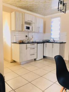 a kitchen with white cabinets and a black chair at Blanc and Bold in Kempton Park +11 photos